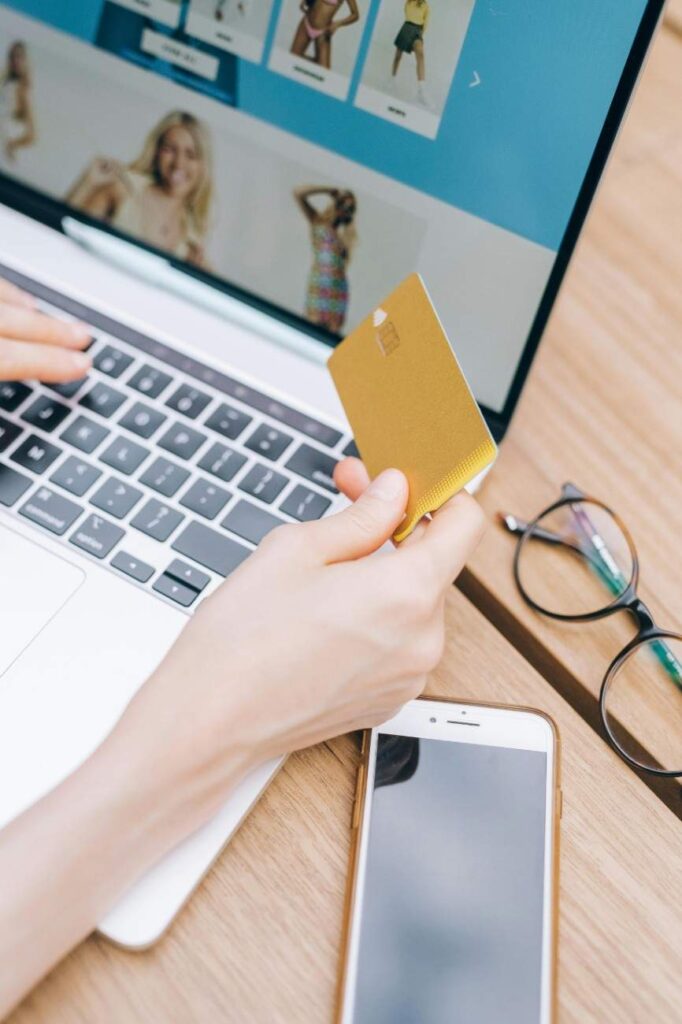 A person holding credit card, ready to do online shopping on laptop